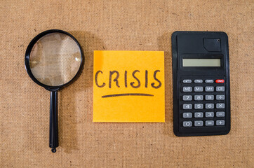 "crisis" on a sticker with a calculator and a magnifying glass.