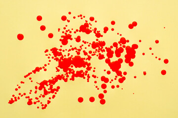 Red oil paint splashes on yellow paper.