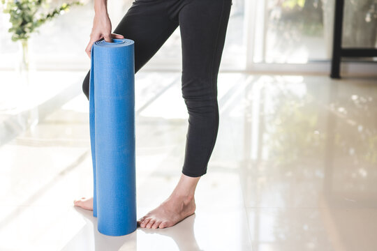 Woman Wearing Black Workout Clothes And Blue Yoga Mat Poses After Exercise.