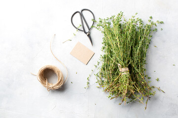 Fresh thyme, scissors, string and tag on the gray table. The view from the top.