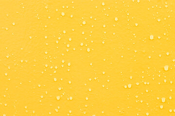 Blue water drops on yellow wooden background.