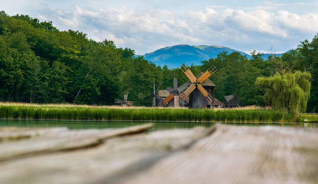 windmills near a lake, with mountains and clouds in the background, in Astra ethnographic museum, Sibiu, Romania