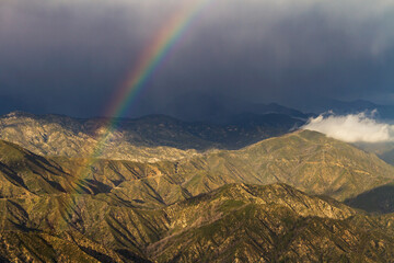 A rainbow stretches over the San Gabriel Mountains of Southern California