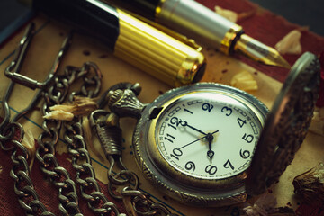 Fototapeta premium Vintage pocket watch and brass pen on old book. At 8 o'clock in morning. Education and vintage style concept.