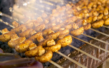 Delicious juicy marinated mushrooms strung on skewers, cooked on a barbecue grill. A lot of mushrooms on a beautiful Sunny day are cooked on the grill over hot coals, fried until Golden brown, 