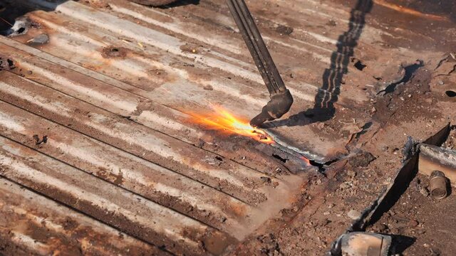 Cutting metal sheet at the scrap yard with oxygen cutter, close up - waste management and recycling metals
