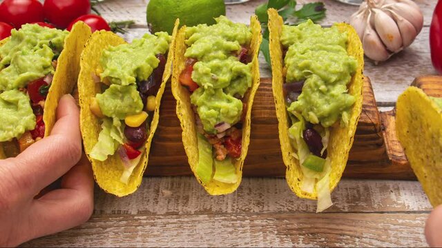 Making delicious hard shell tacos, stuffing and assembling the popular mexican dish - hands reaching to get a savory bite - close up, stop motion animation