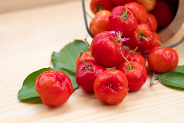 Acerola cherry in wooden bucket on wooden background. Select  focus, Barbados cherry, Malpighia emarginata, high vitamin . Acerola fruit.