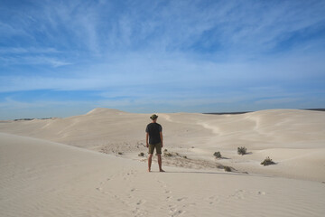 lonely man standing back on a sandy beach
