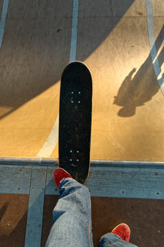 Skateboarder standing at the top of a ramp.
