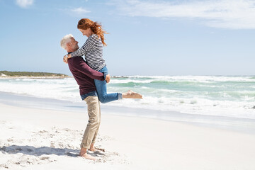 Senior man lifting mature woman on beach
