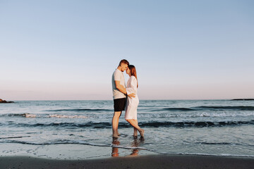 Couple in love having romantic tender moments at sunset on the beach - Young lovers having tender moments in summer vacation - Love concept - Soft focus on them - Matte filter with soft blue vignette