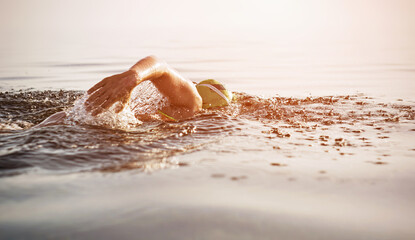 Unknown triathlon swimmer at sea. athletic young woman swimming freestyle in morning open water