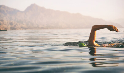 Unknown triathlon swimmer at sea. athletic young woman swimming freestyle in morning open water