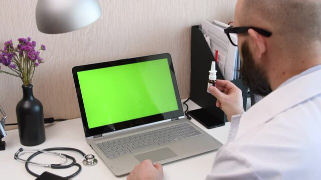 Telemedicine. Consultation with physician through mobile video call. Doctor talking to comlaining patient using video chat application on laptop and prescribes a medication. Green screen chromakey.