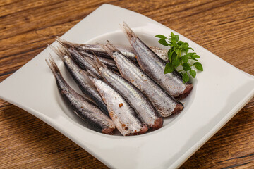 Anchovies in the bowl served basil leaves