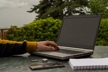a young student handles his laptop at his outdoor work table