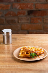 Viennese waffles on a disposable plate with caramel syrup, cinnamon powder and mint