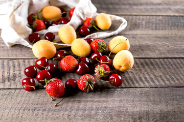 Reusable bag with apricot, strawberry and cherry on wooden table background. Zero waste concept