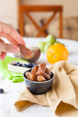Vertical shot of a healthy breakfast table with a small bowl of delicious Algerian dates and other fruits on the background.