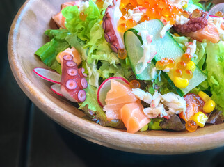 Vegetable salad seafood mixed with raw sliced salmon, octopus, caviar, green lettuce in a bowl, Japanese food