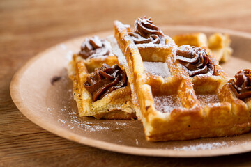 Viennese waffles on a disposable plate with peanut butter, icing sugar and mint.