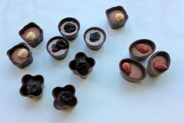 Set of chocolate candies with almond, dried cherries,  raisins, and hazelnut on white background