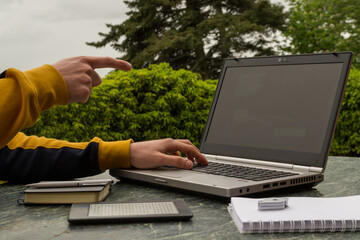 a young man pointing at a laptop at his outdoor work table