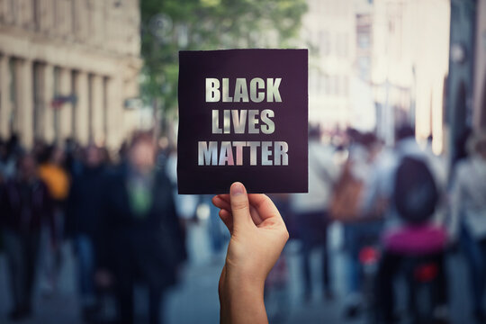 Black Lives Matter, Street Demonstration. Human Hand Holds A Dark Protest Banner, Against Injustice. USA Black People Rights, Social Problems Concept, Racism And Inequality. Stop Discrimination.