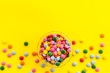 Color candy on yellow table top-down copy space