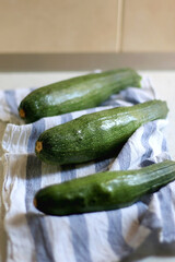 Three homegrown zucchinis on the kitchen counter. Selective focus.
