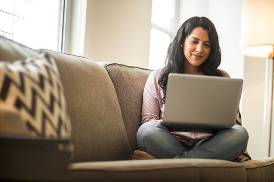 Young woman working at home sitting on a sofa.