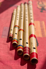 Five north India bamboo flutes on a red table. © Daniel