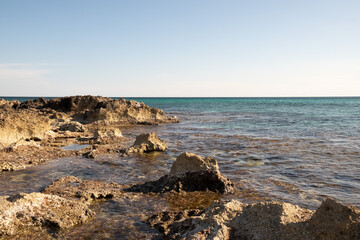 We are in Puglia, South Italy, Salento, a view of the rocky coast bathed by the calm water of the Jonio Sea on a clear afternoon.
