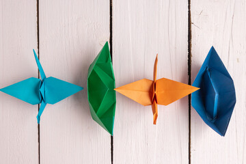 Origami toys made of colored paper lie on a wooden background