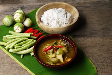 Wooden bowl of Fish organs sour soup  and Rice Noodles on banana leaf  with vegetables  in the kitchen prepare for serving ,Thai local food image for background , selective