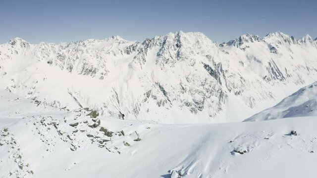 Aerial shot of a splitboarder hiking on top of a mountain in Switzerland.