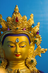 Vetrical view of gold covered statue of tibetan buddhist deity of compassion Chenrezig.