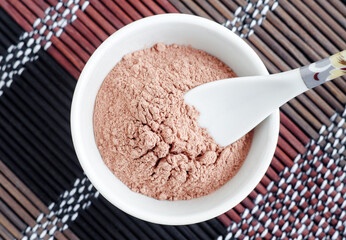 Pink bentonite clay powder in the bowl and spoon. Clay texture close up. Diy facial or hair mask, dry shampoo and body wrap recipe. Natural beauty treatment and spa. Top view, copy space