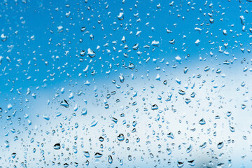 Frozen drops of rain on glass on background of blue sky.