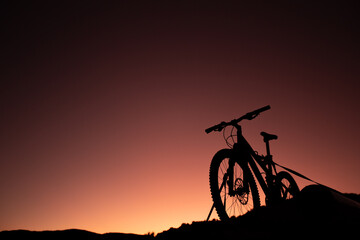 Obraz premium Silhouette of Mountain Bike, Dirt bike on the car roof rack in the countryside at the sunset,Bicycles built for traveling on dirt road.