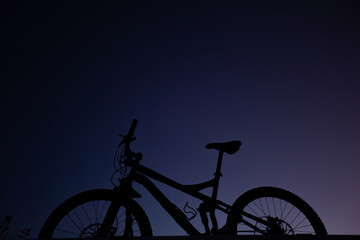 Silhouette of Mountain Bike, Dirt bike on the car roof rack in the countryside at the sunset,Bicycles built for traveling on dirt road.