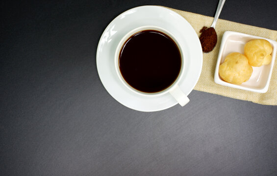 Black coffee in a white mug on a black background with sweets in arrangement for advertising background images, shop decoration, brochures, books and more.