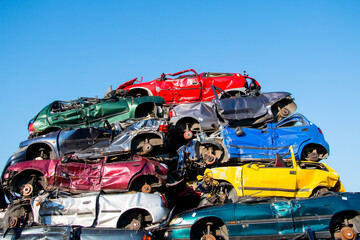 Cars in different colors stacked on a scrap yard