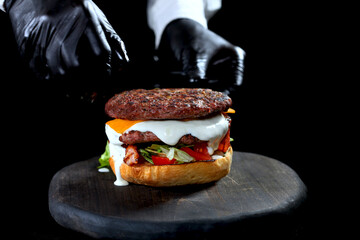 The chef puts the cutlet in the hamburger. Food preparation. An unrecognizable photo. Copy of the space. Unrecognizable photo.