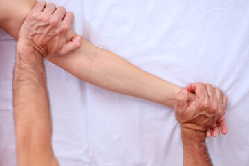 Fototapeta na wymiar Shiatsu massage. Close up of massagers hands working on patients hand and lower shoulder.