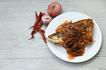 Fish head sambal in white plate on wooden table 
