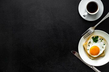 Obraz na płótnie Canvas Fried eggs sandwich on plate - black background top-down copy space