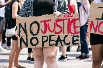 Midsection of woman holding No Justice, No Peace Sign