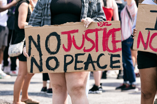 Midsection of woman holding No Justice, No Peace Sign